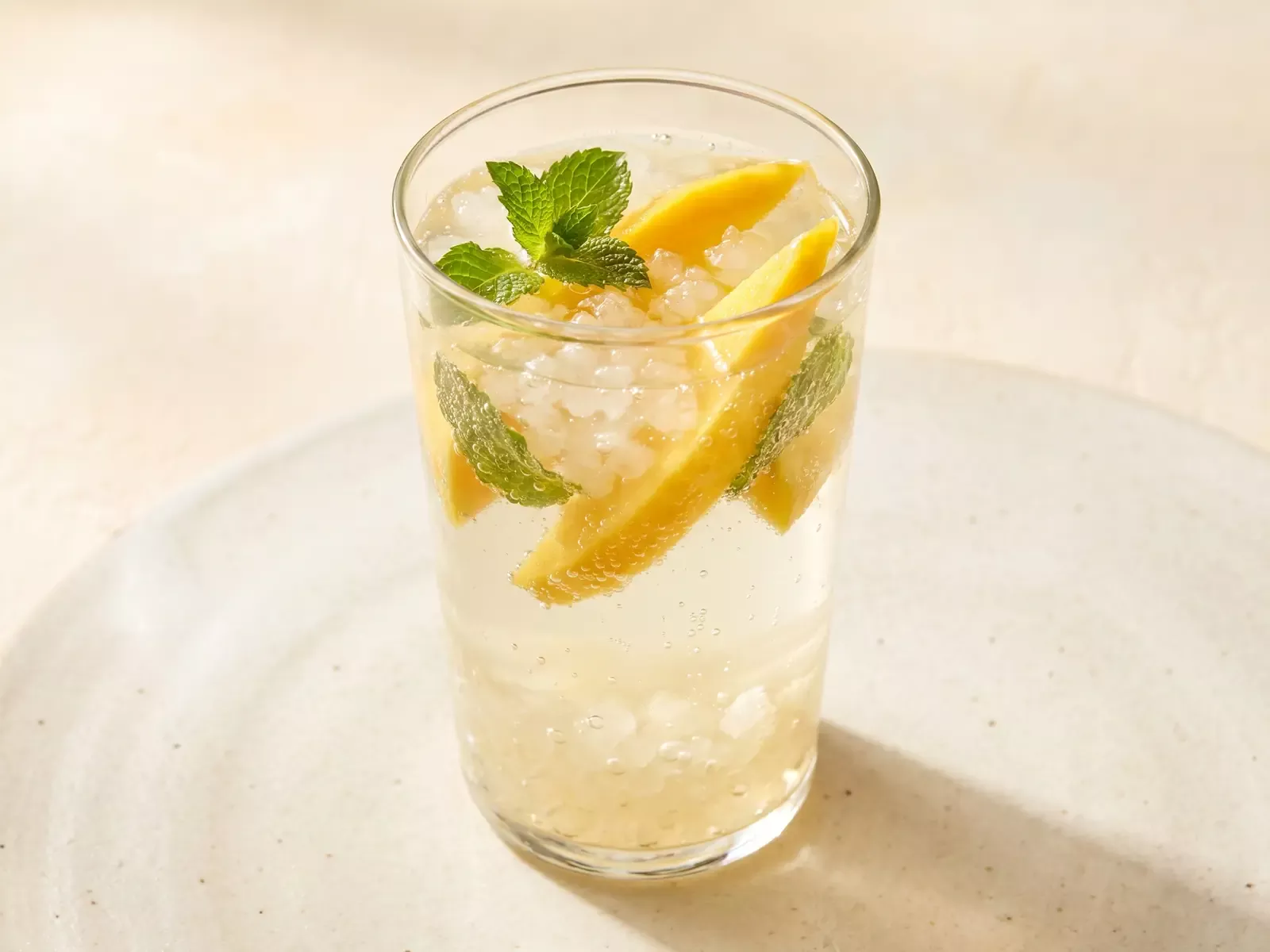 Verre de k&eacute;fir d&rsquo;eau avec mangue et menthe, pr&eacute;sent&eacute; sous une lumi&egrave;re chaude et douce.